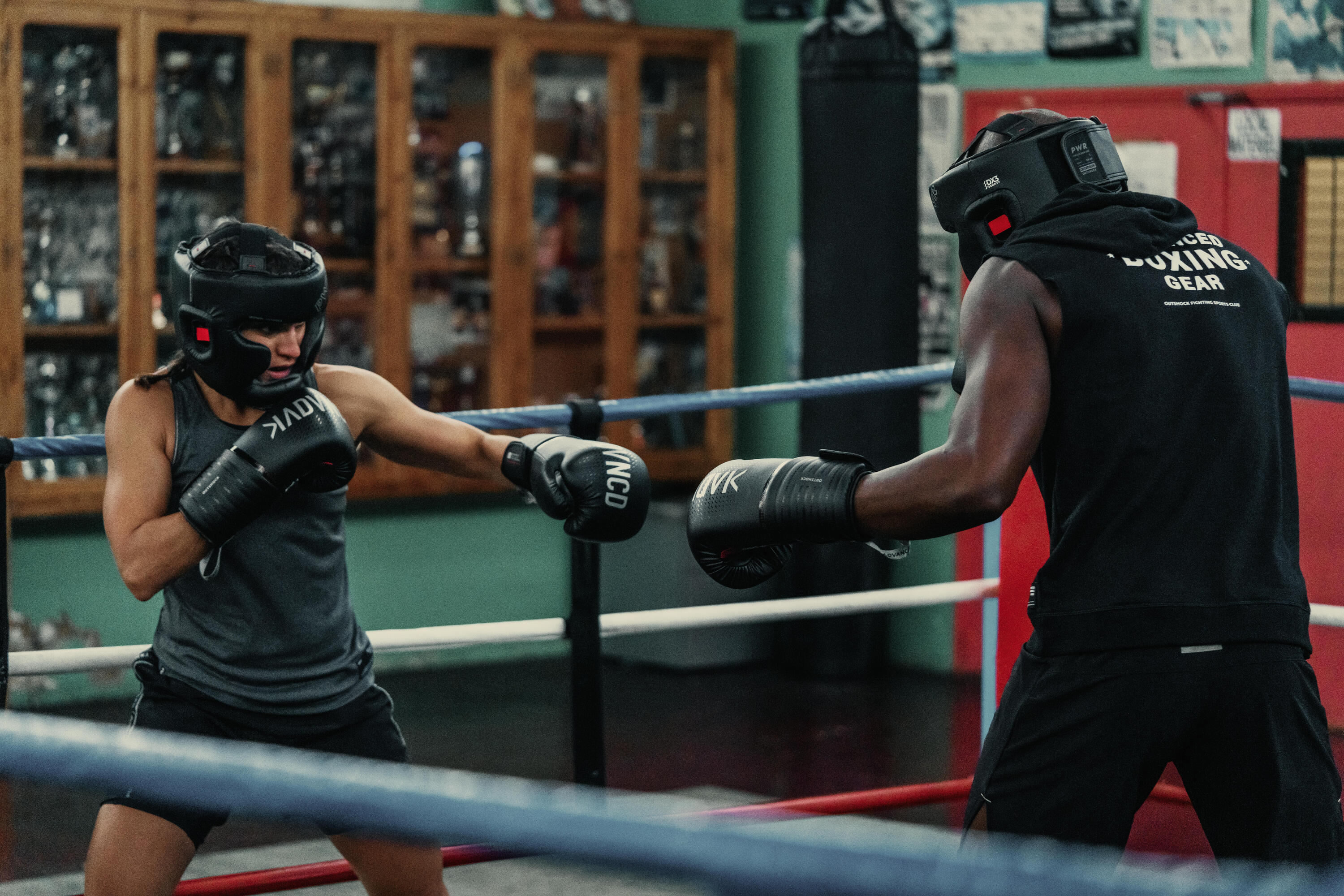 Zwei Boxer beim Sparring im Ring mit Kopfschutz und Handschuhen in einem traditionellen Boxclub.