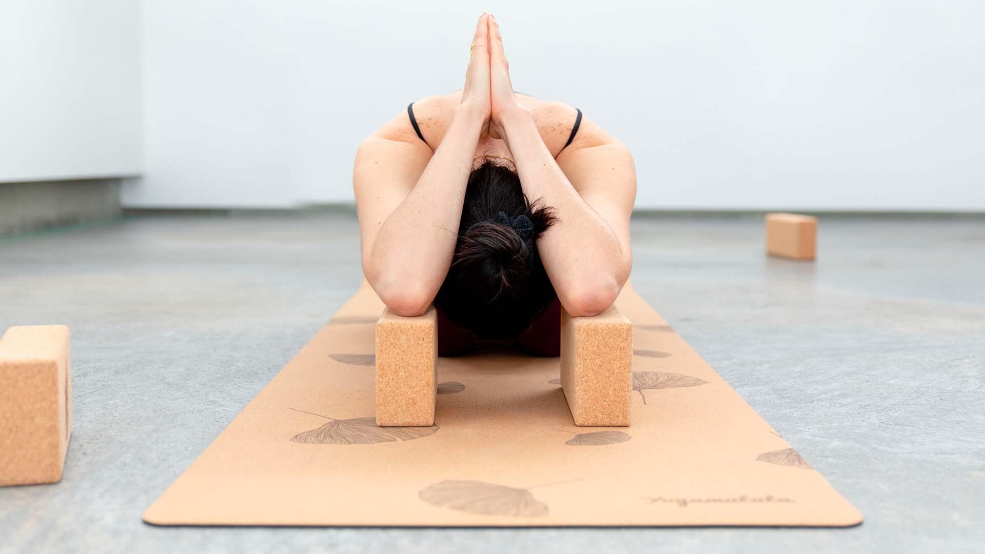 Woman using two cork yoga blocks to support a forward fold