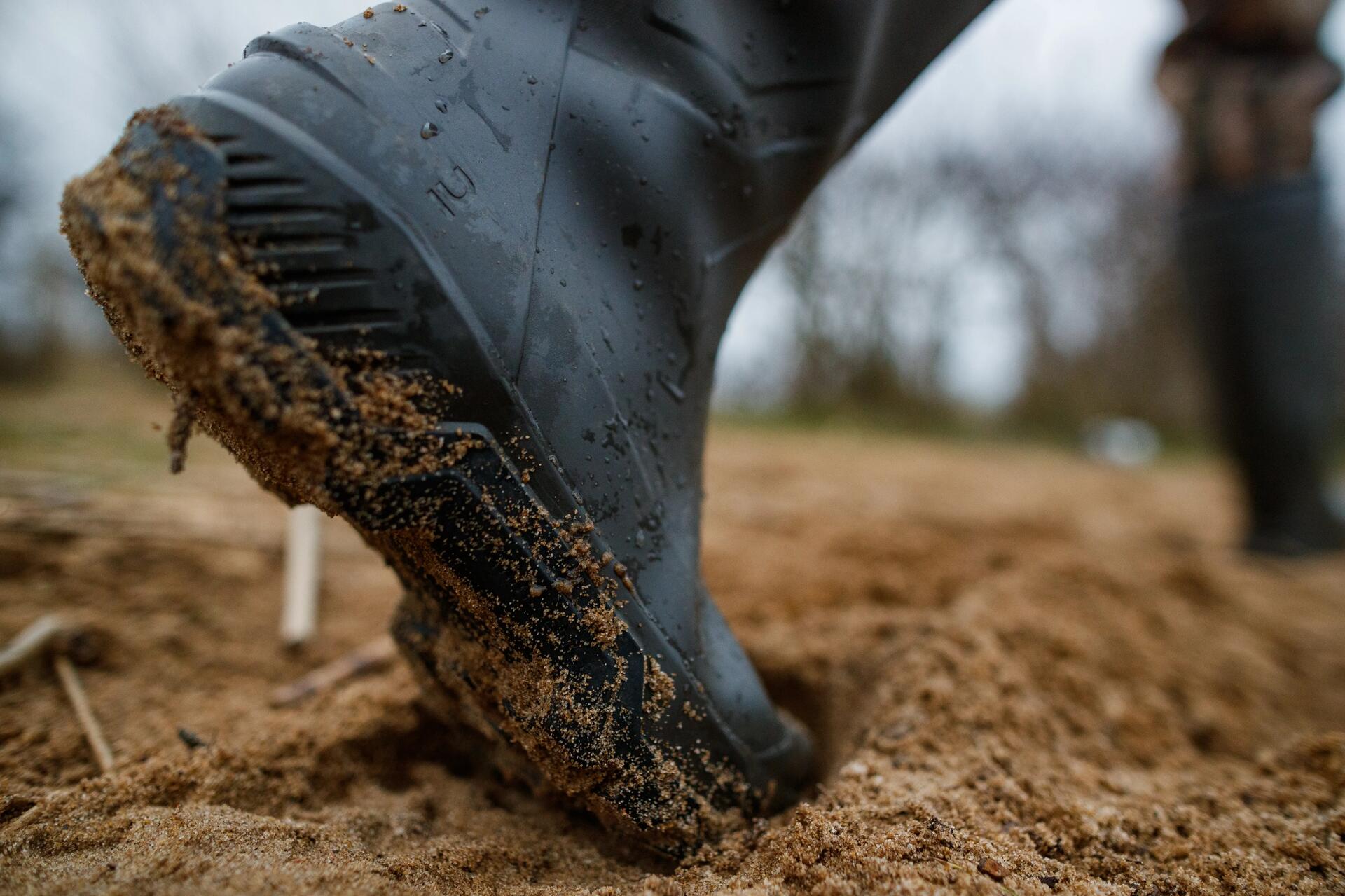 Un chasseur au gibier d'eau qui marche dans le sable avec une paire de bottes de chasse aux pieds