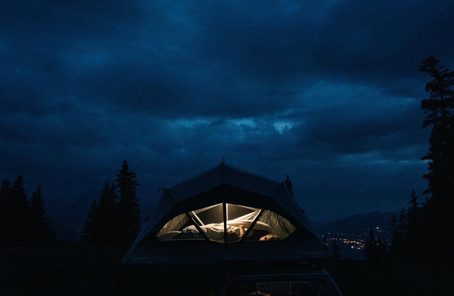 Kobieta śpiąca pod namiotem podczas pochmurnej nocy