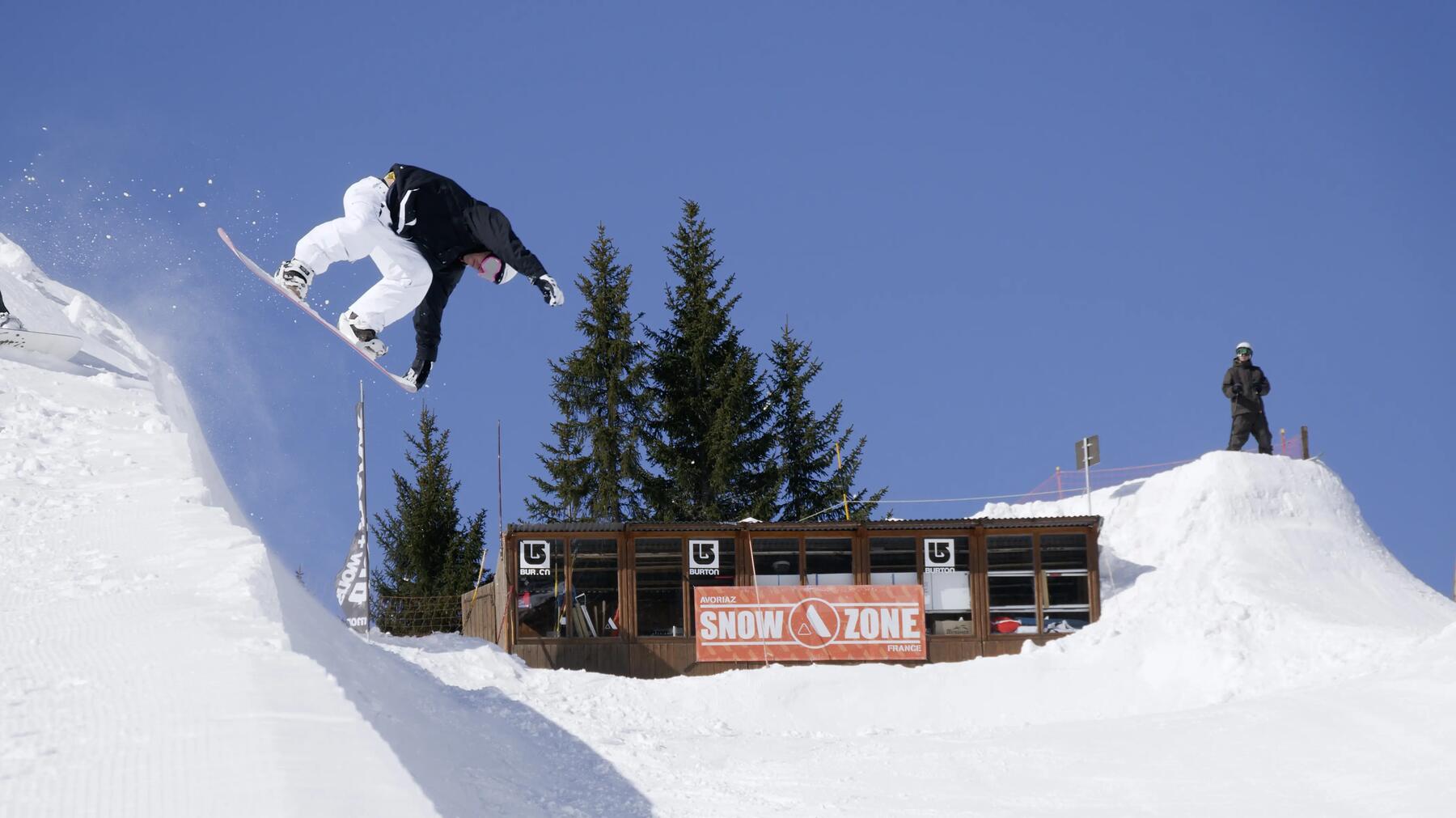 Snowboarder trenujący skok na desce snowboardowej w snowparku