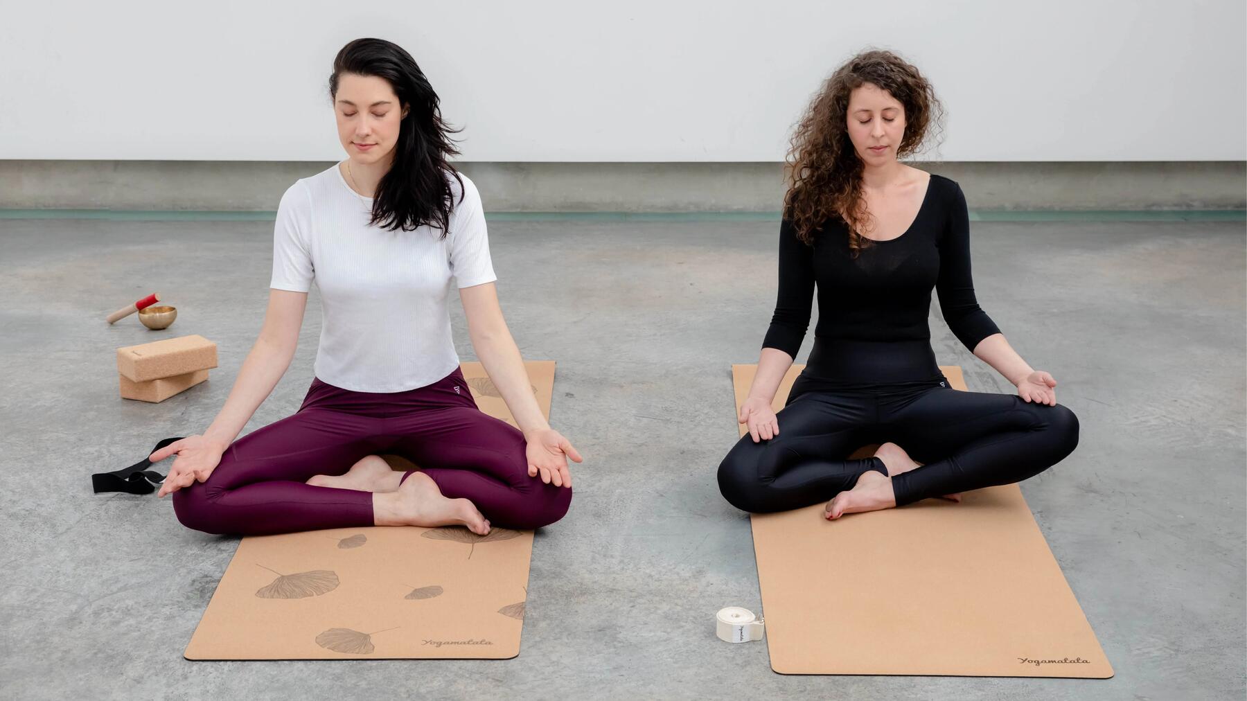 Zwei Frauen auf Korkyogamatten in einem hellem Raum beim Yoga
