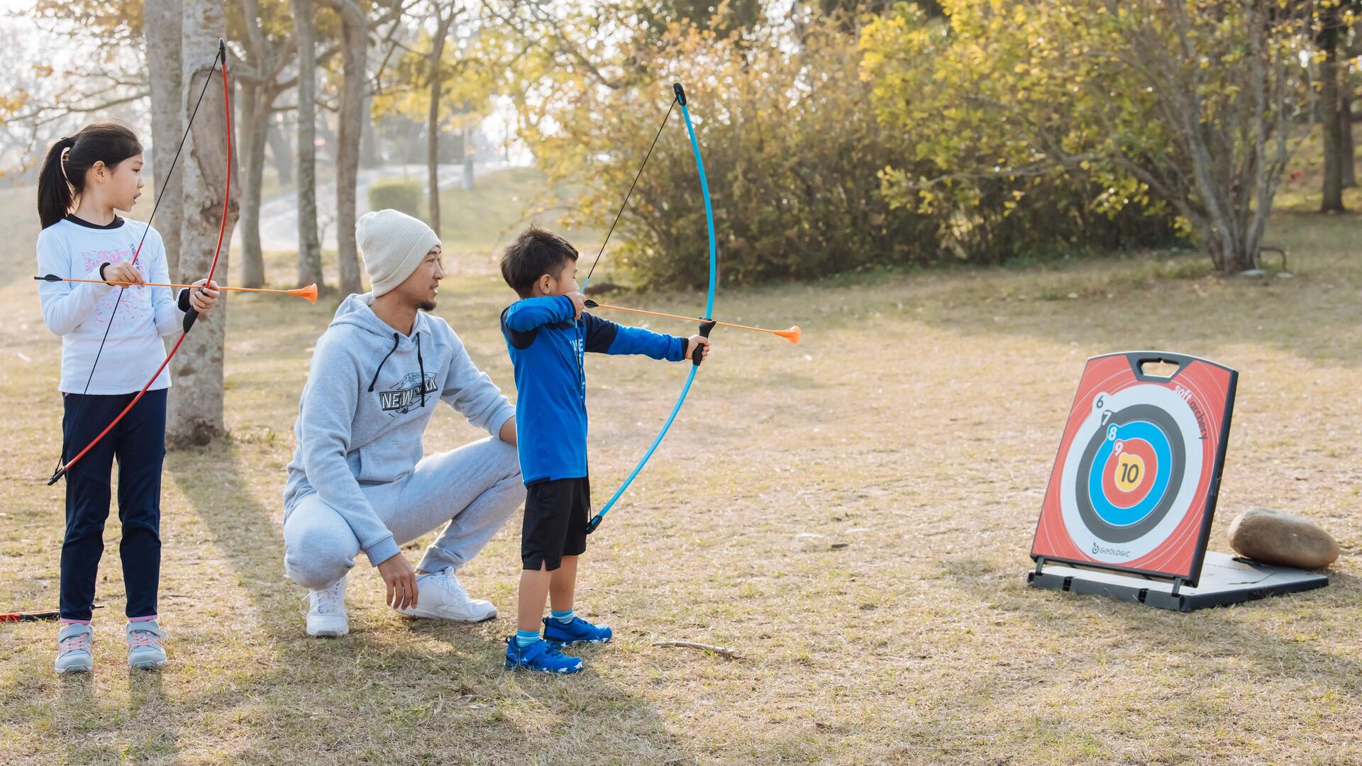 A man and two kids using an archery set 