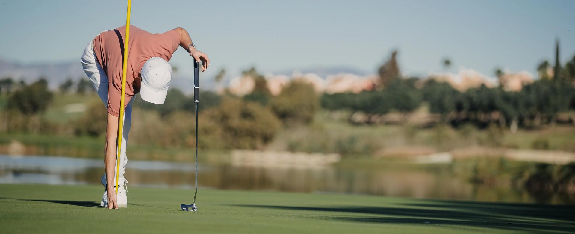 Hombre recogiendo bola de golf del hoyo