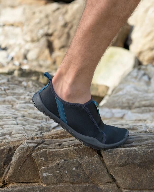 Man stapt op een grote rots met zijn Aquashoes aan