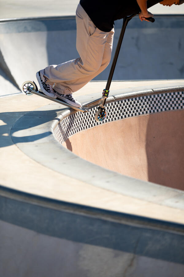 Osoba na trotinetu na ivici bazena u skejt parku.