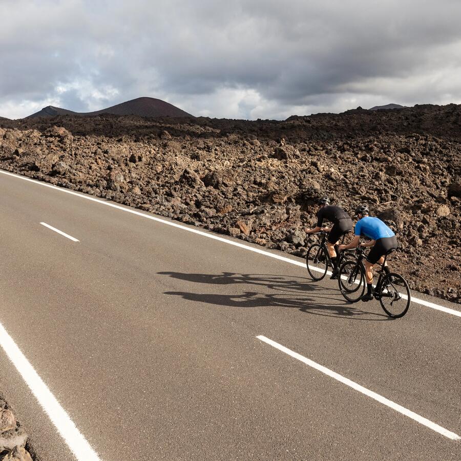 2 cyclistes sur une route entourée de roches volcaniques.