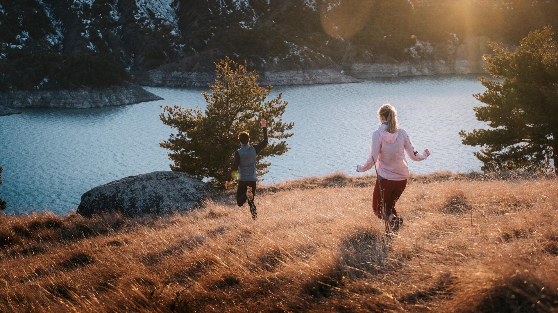 man and woman running through a grassy trail