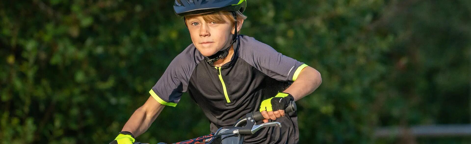 chłopiec w kasku i odzieży rowerowej jadący na rowerze