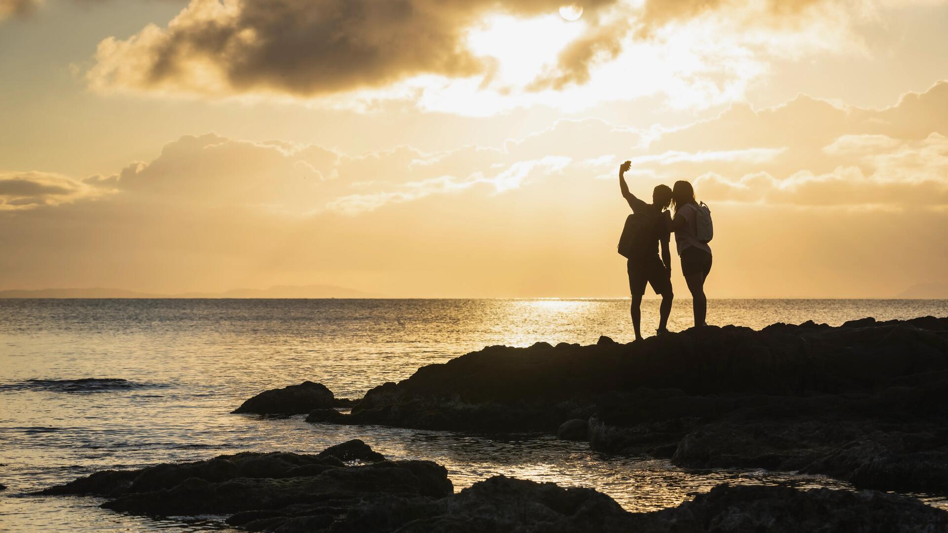 casal a tirar fotografia ao por do sol