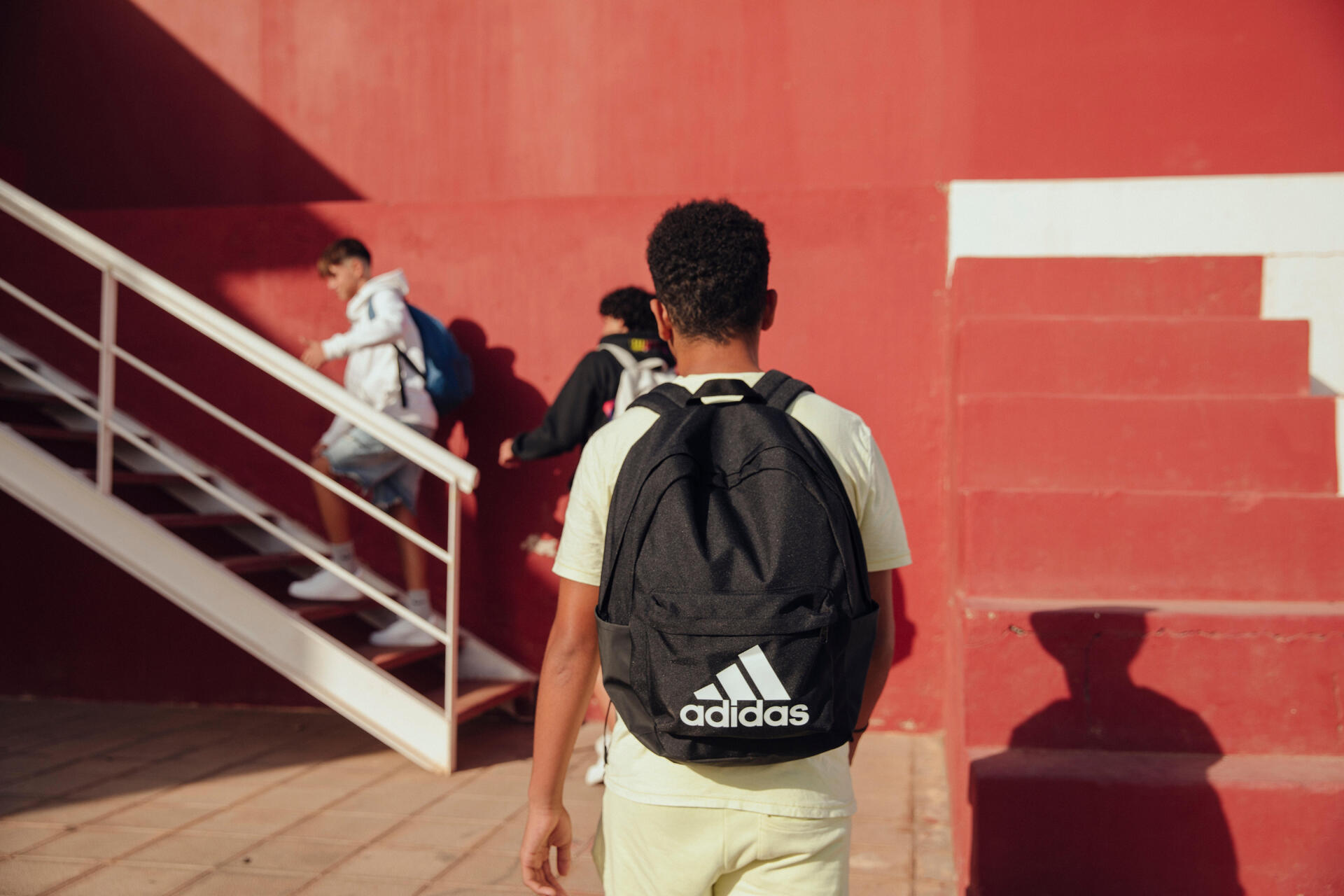a schoolboy wearing a classic Adidas backpack while walking to school