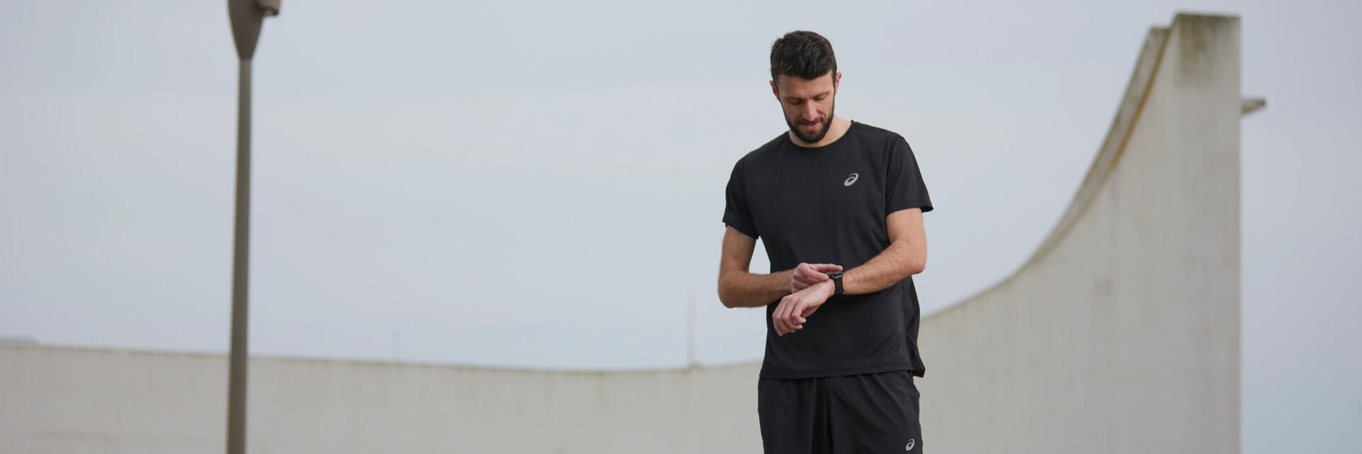 Mężczyzna naciskający przycisk na założonym na ręku zegarku sportowym