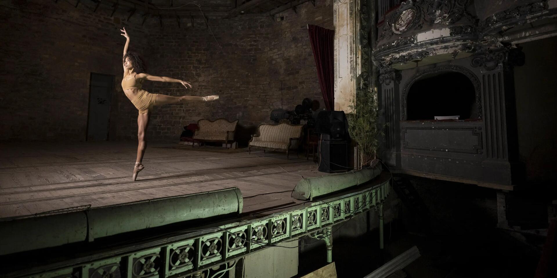 kobieta w staniku i szortach fitness trenująca balet na scenie teatru