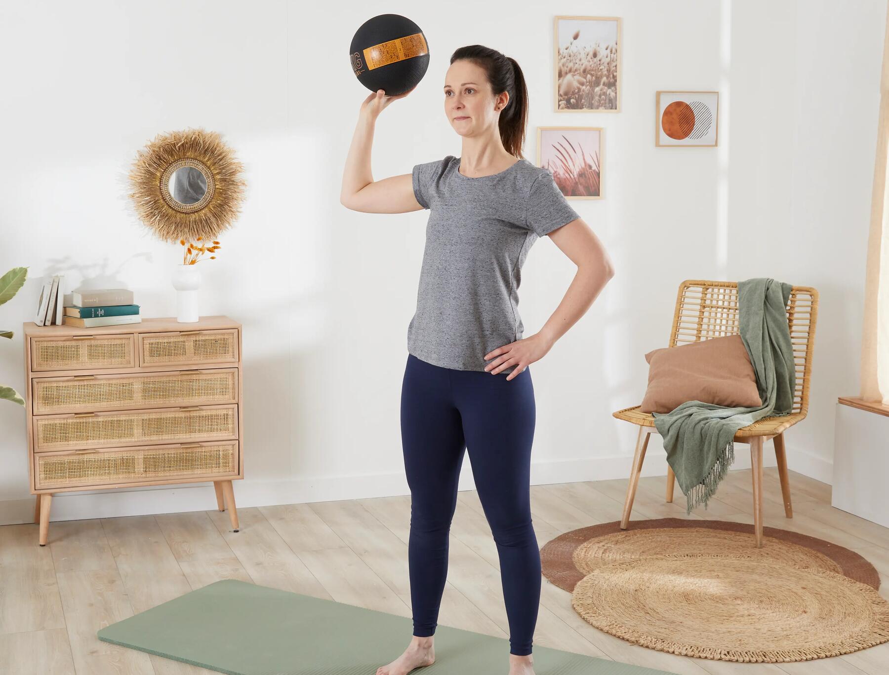 kobieta w odzieży fitness trenująca z piłką lekarską na macie do ćwiczeń