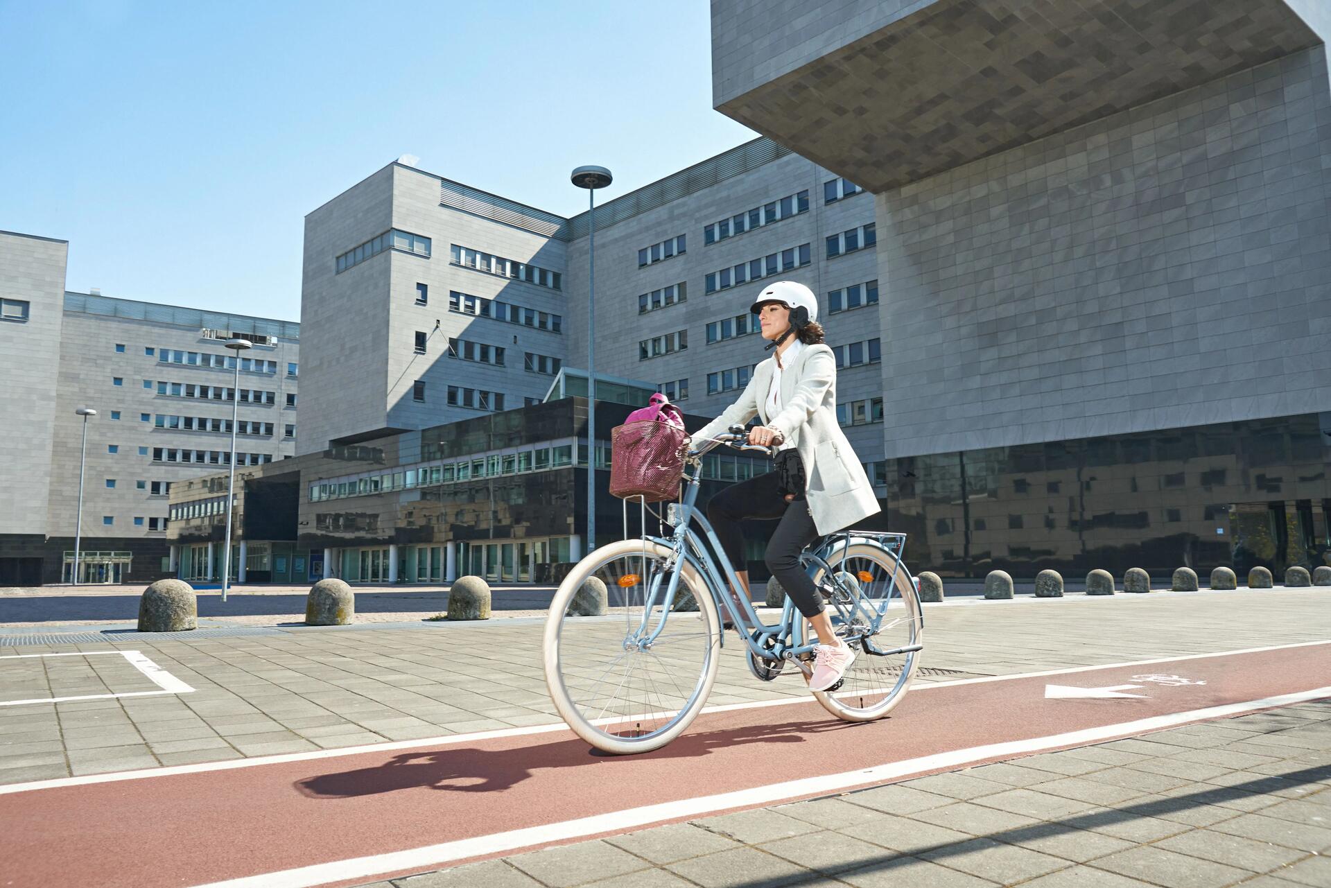Kobieta jadąca na rowerze po ścieżce rowerowej zbliżająca się do przejścia dla pieszych