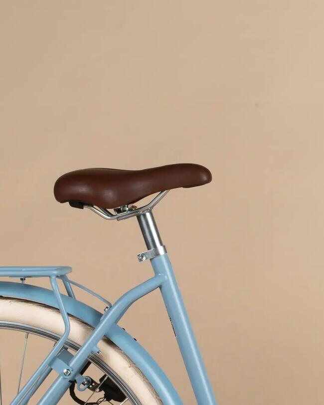 Brauner komfortabler Ledersattel auf blauem Fahrrad, neutraler warmer Hintergrund