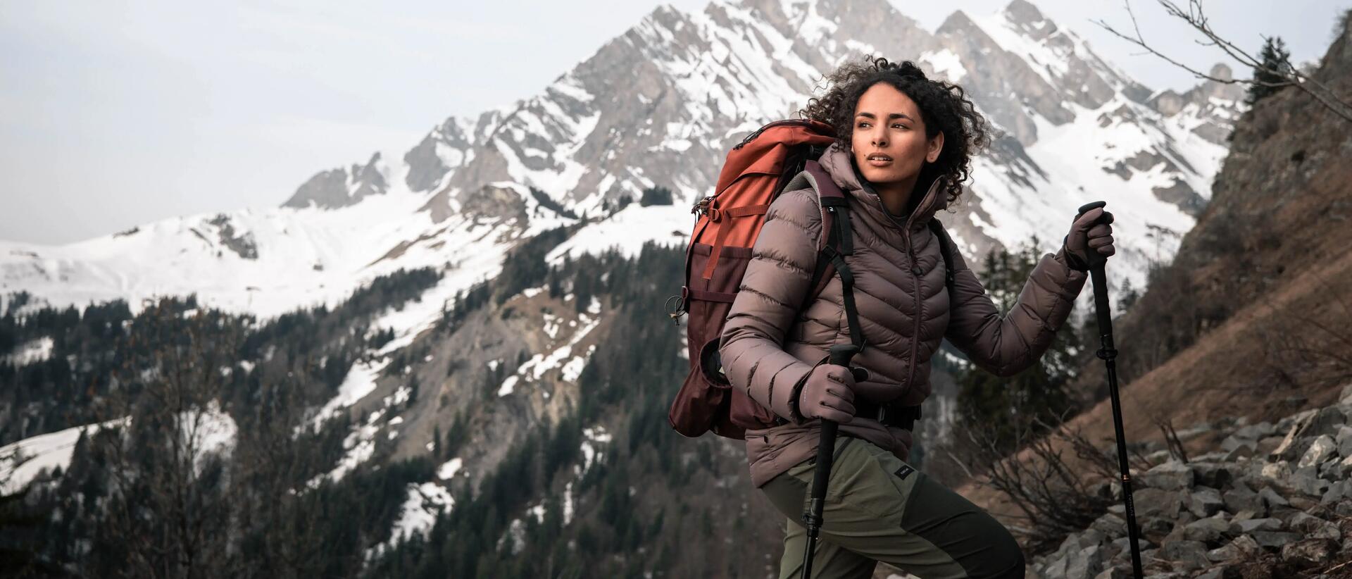 Woman wearing hiking backpack, hiking snowy mountain.
