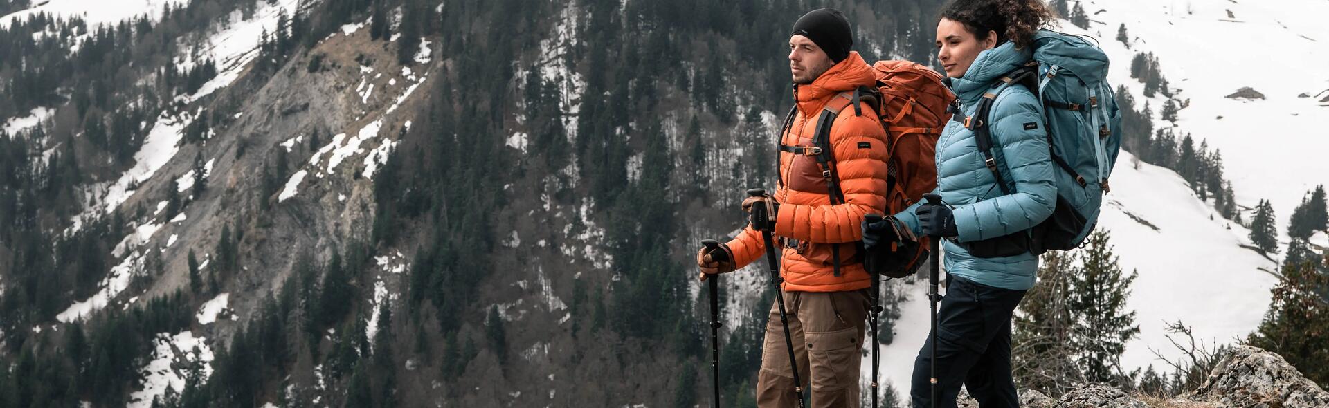 kobieta i mężczyzna z plecakami turystycznymi na plecach  trzymający kijki trekkingowe stojąc w górach