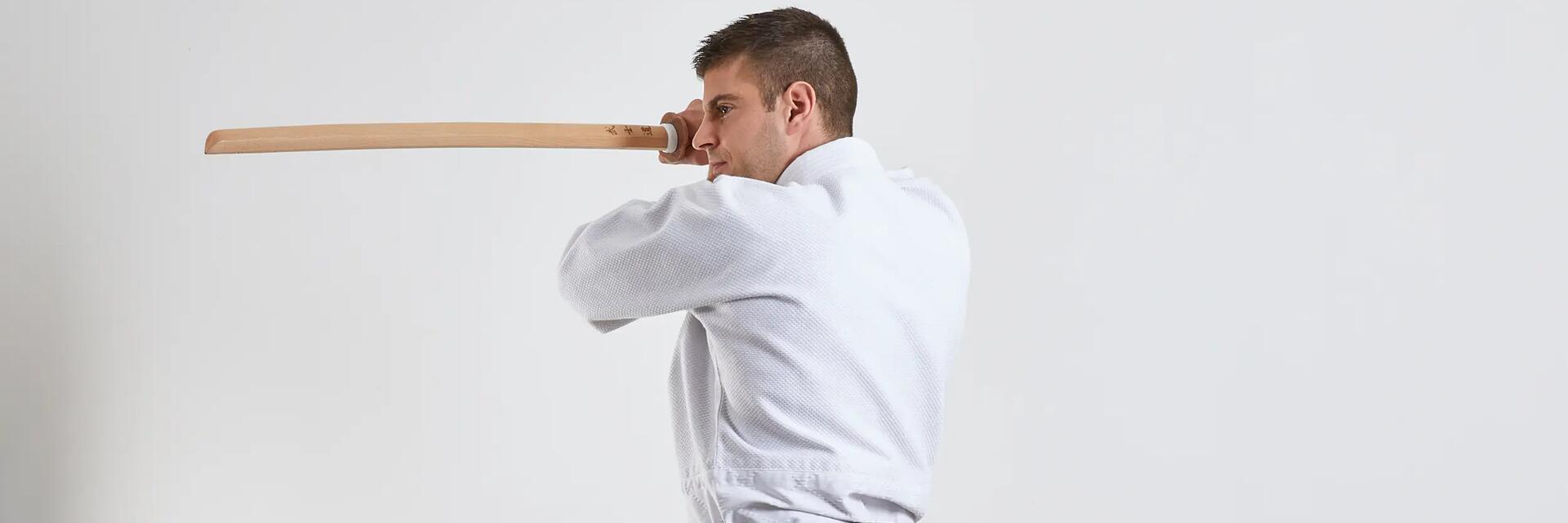Mężczyzna w karatedze trenujący aikido trzymający w ręku bokken