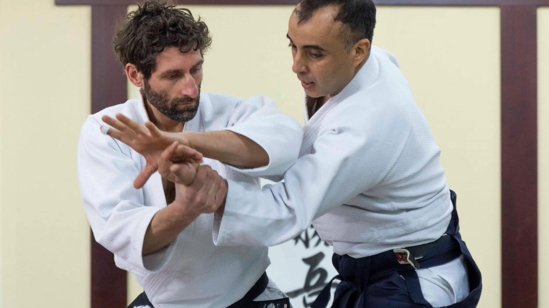 Trener aikido poprawiający technikę kursantowi na treningu