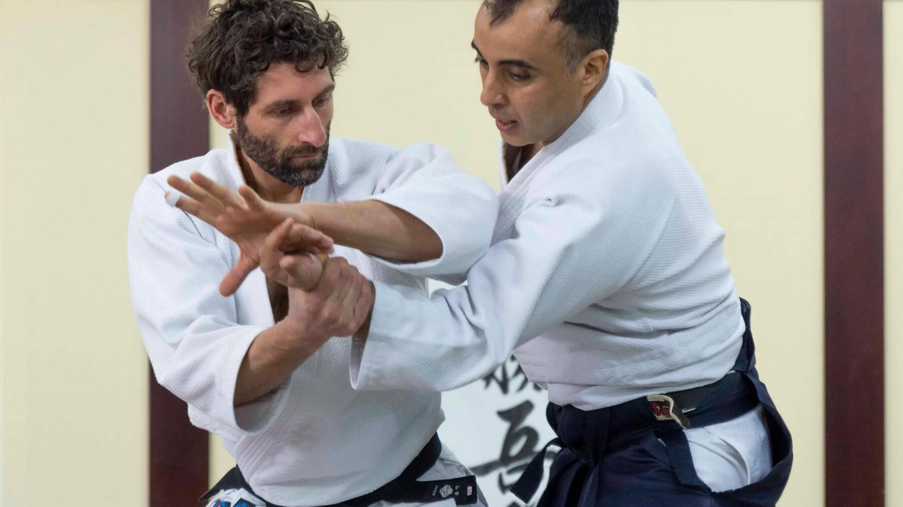 Trener aikido poprawiający technikę kursantowi na treningu