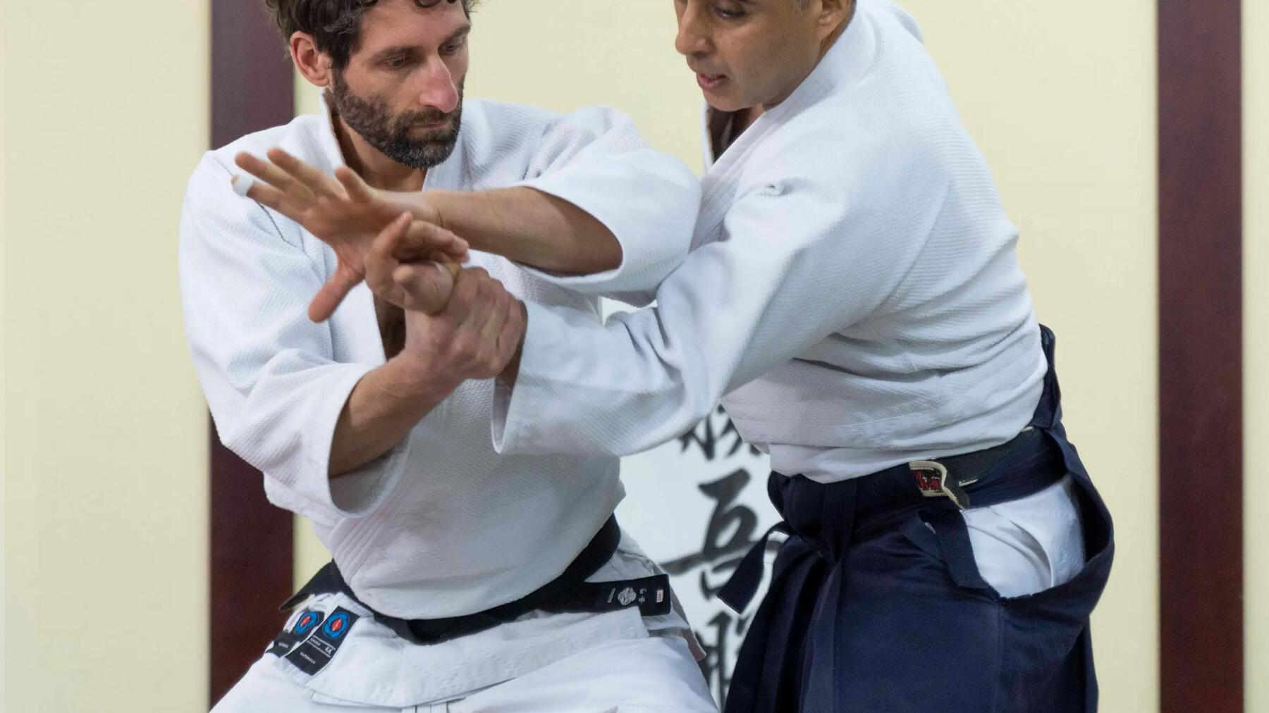 Trener aikido poprawiający technikę kursantowi na treningu