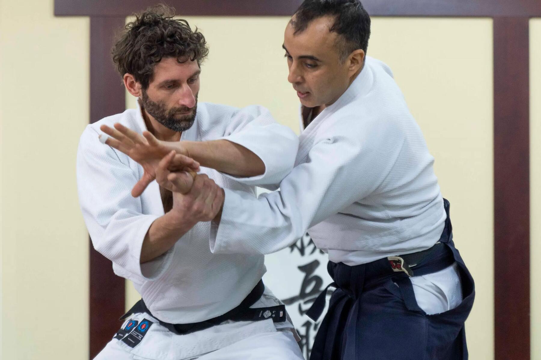 Trener aikido poprawiający technikę kursantowi na treningu