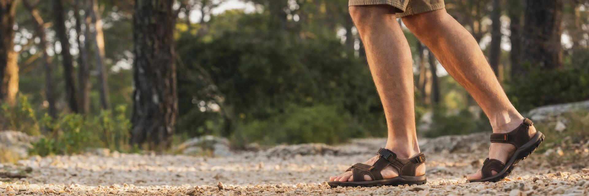 Mężczyzna w sandałach trekkingowych idący po leśnej ścieżce w górach