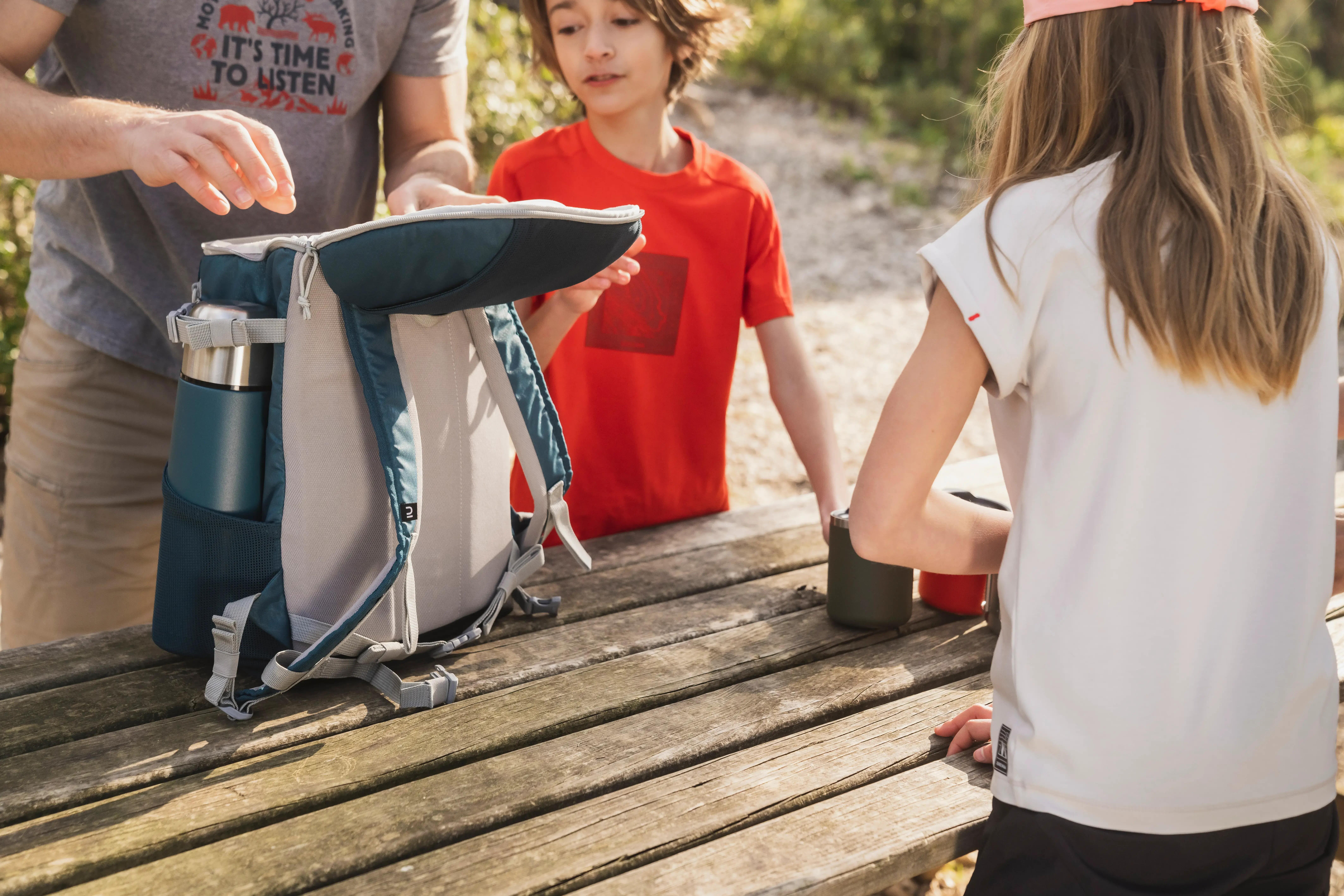 Hikers sharing a hot drink from an insulated water bottle in the mountains.