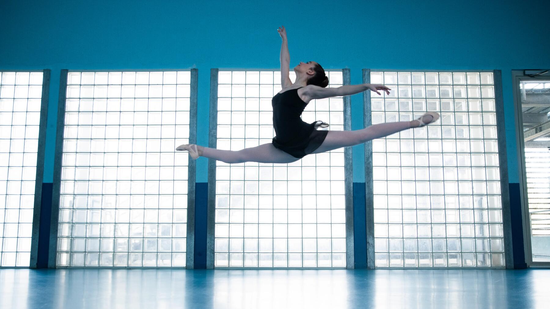 Balletttänzerin beim Spagatsprung im Tanzstudio