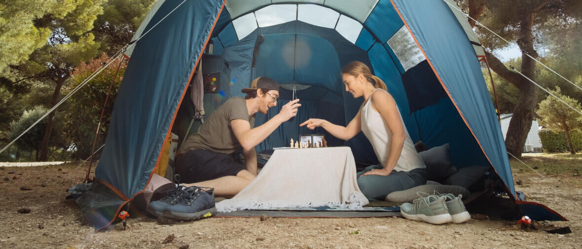 homem e mulher a jogar xadrez numa tenda em acampamento decathlon