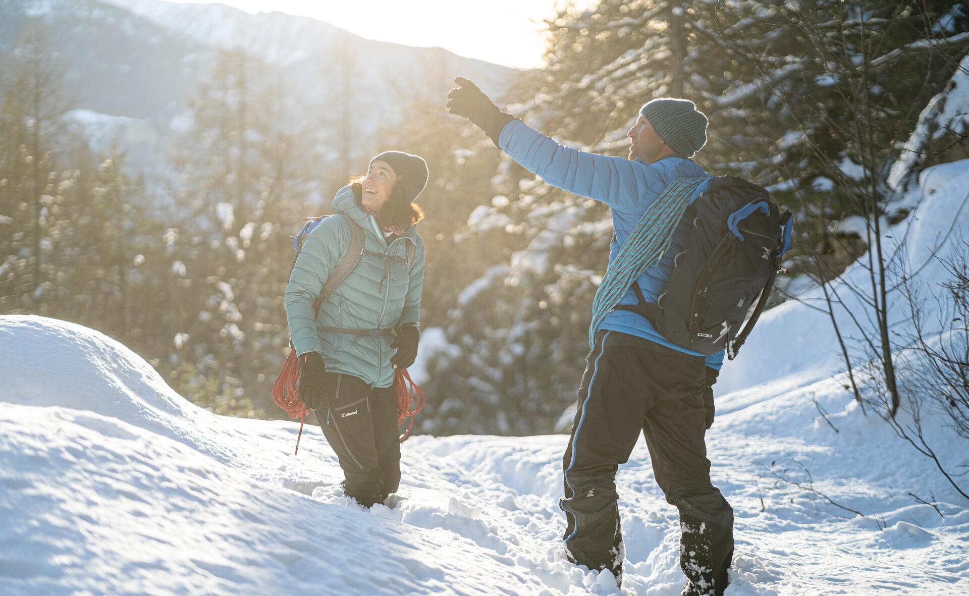 kobieta i mężczyzna w zimowej odzieży trekkingowej stojący w śniegu w górach