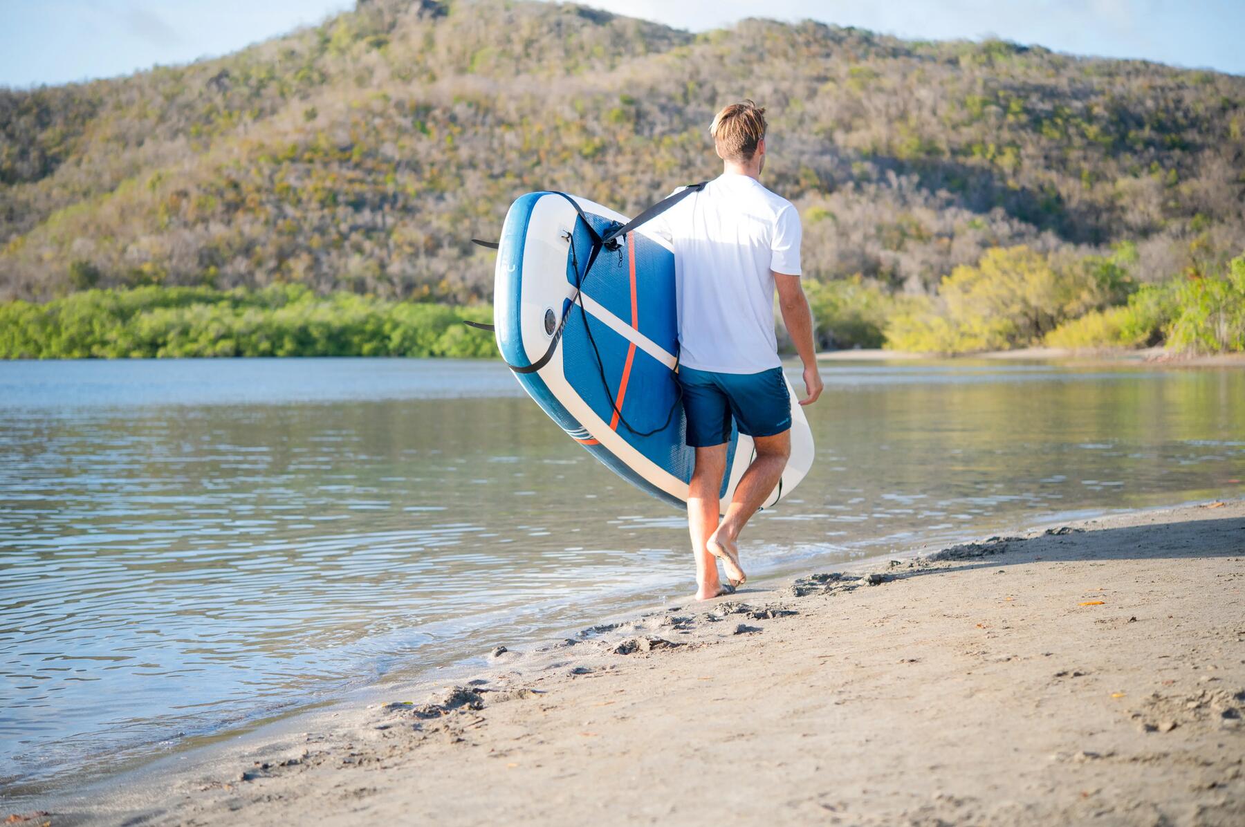 hombre transportando tabla paddle surf a pie