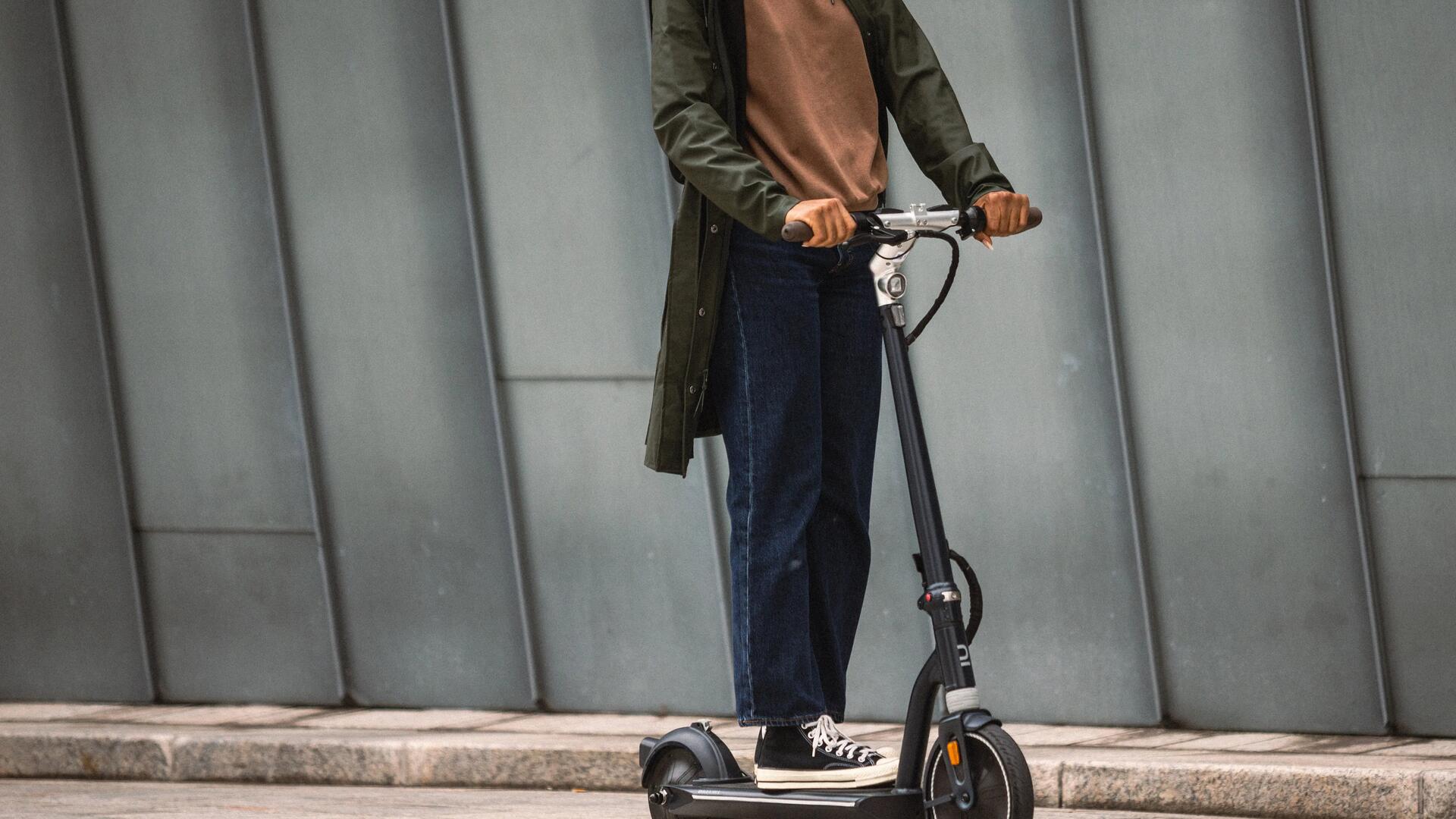 kobieta jadąca na hulajnodze elektrycznej w kasku