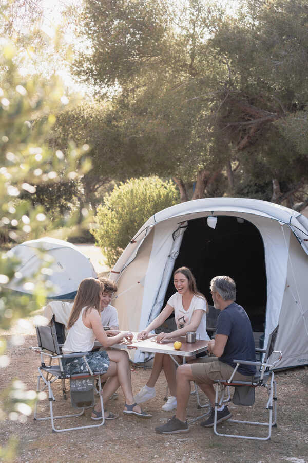 Family camping sitting outside tent