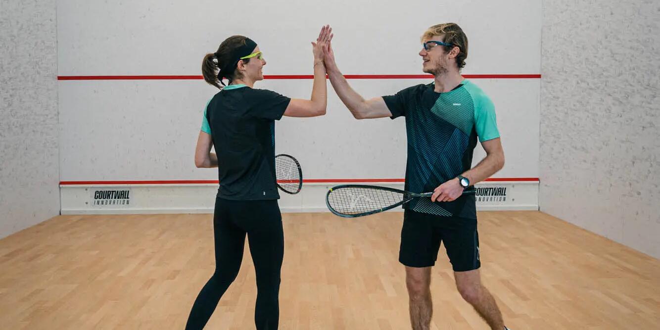 Mężczyzna i kobieta przybijający sobie piątke po skończonym meczu squasha
