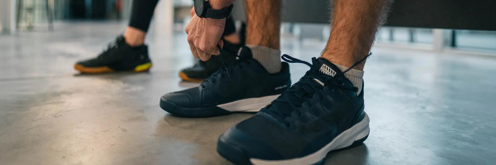 mężczyzna zawiązujący buty do squasha przed treningiem