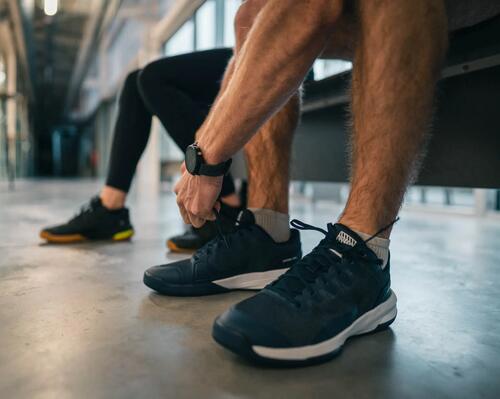 mężczyzna zawiązujący buty do squasha przed treningiem