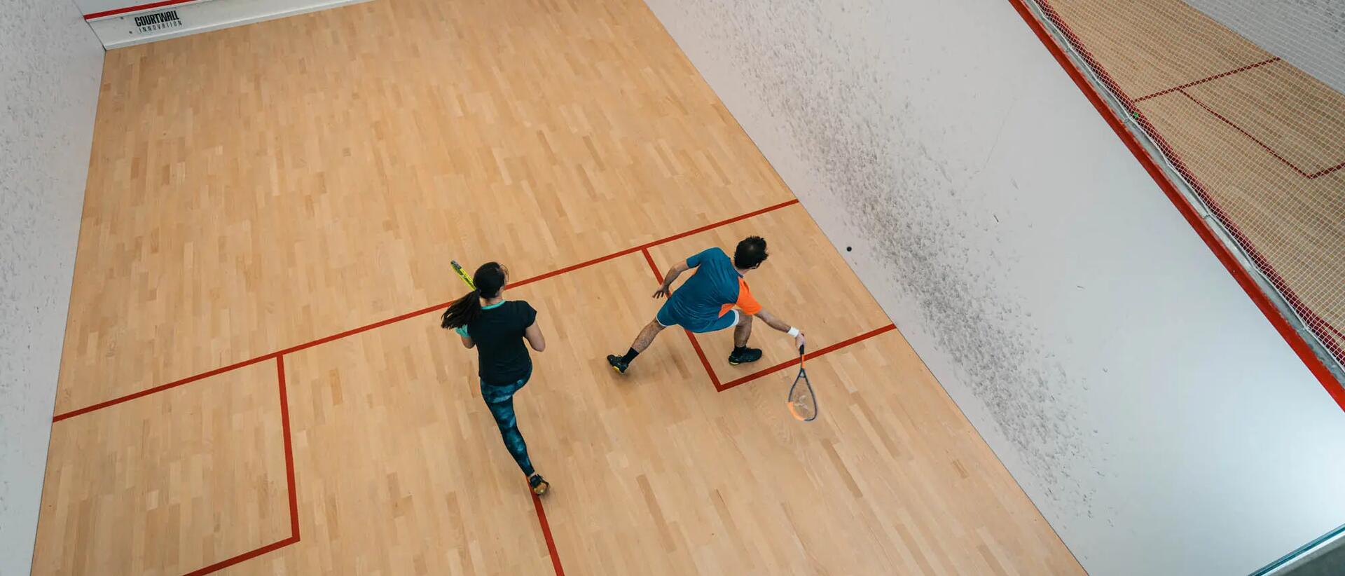 kobieta i mężczyzna grający w squasha na boisku