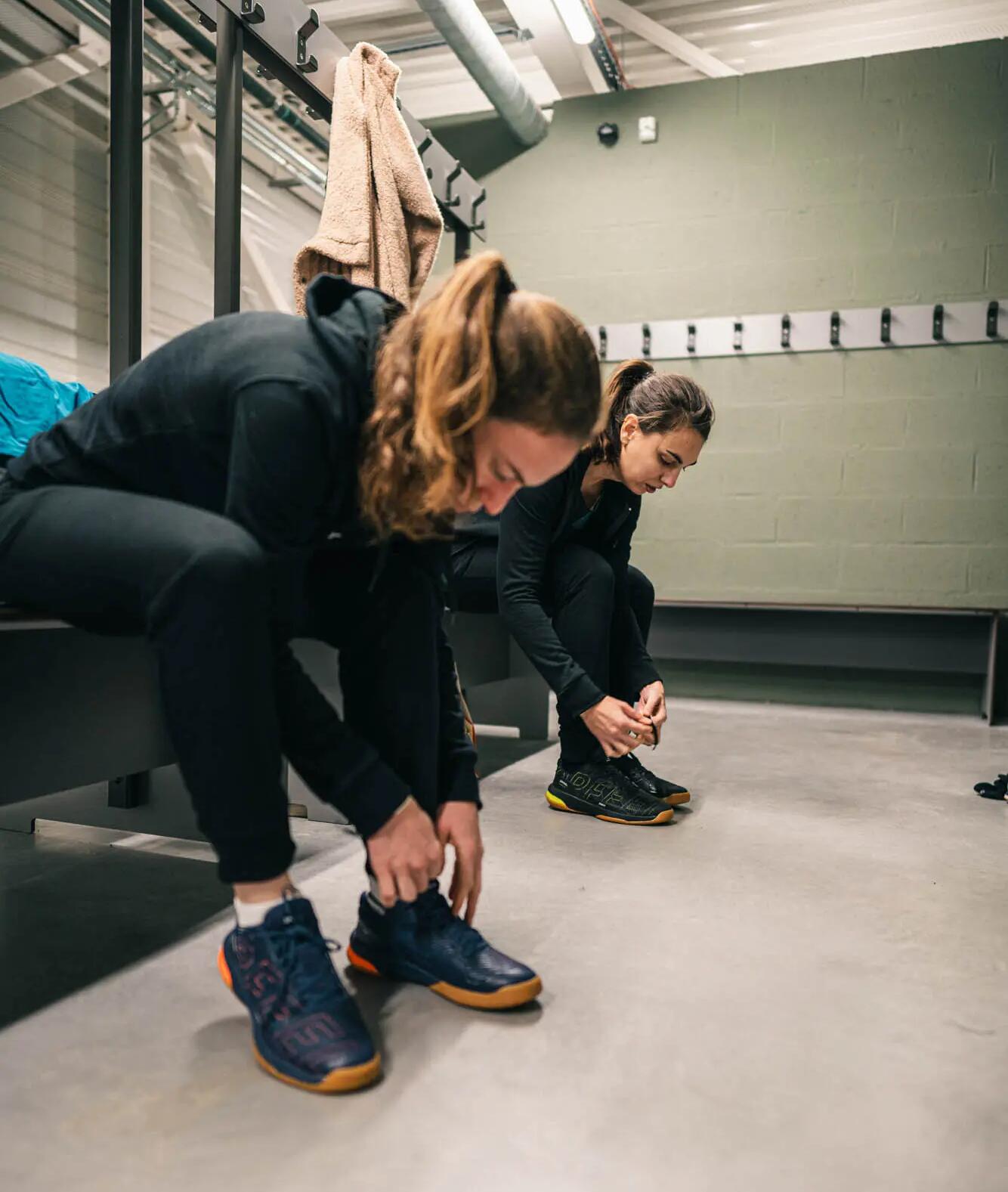 kobiety zawiązujące buty do squasha w szatni