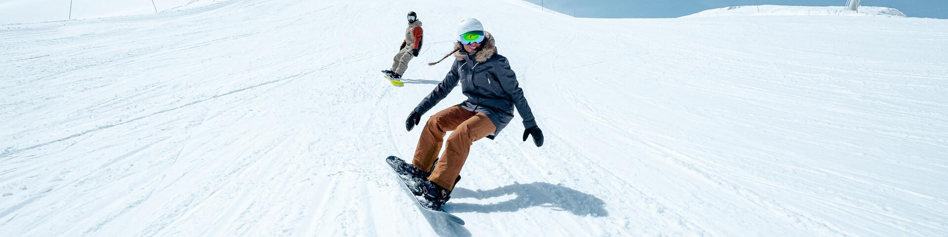 kobieta i mężczyzna zjeżdżają ze stoku na deskach snowboardowych