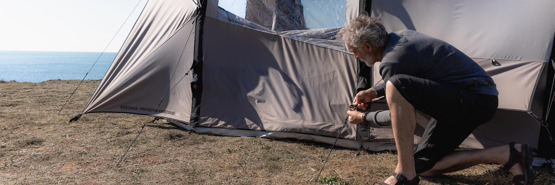 Mężczyzna rozkładający namiot turystyczny na płaskim podłożu