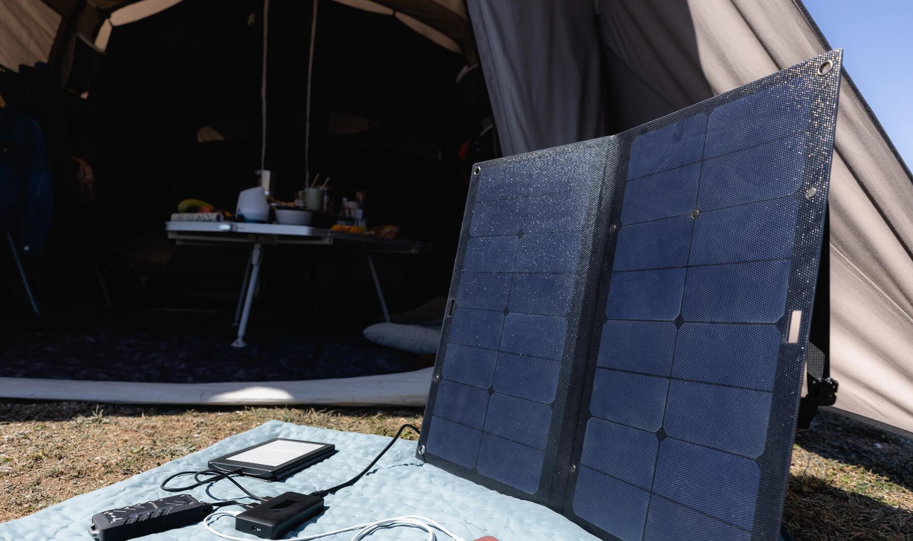 Panel solarny turystyczny rozłożony na macie przed namiotem 