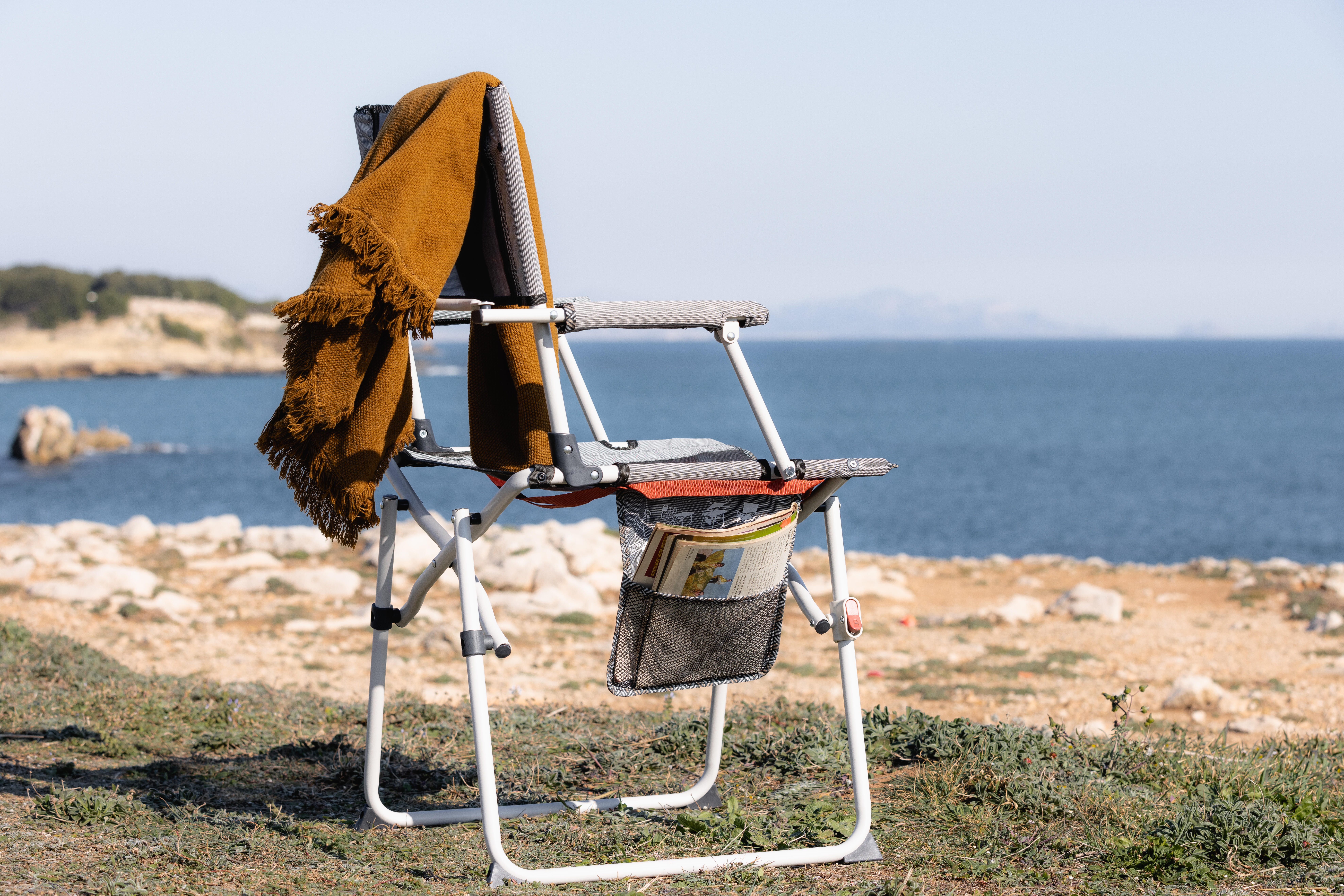 Padded picnic chair with armrests beside the coast