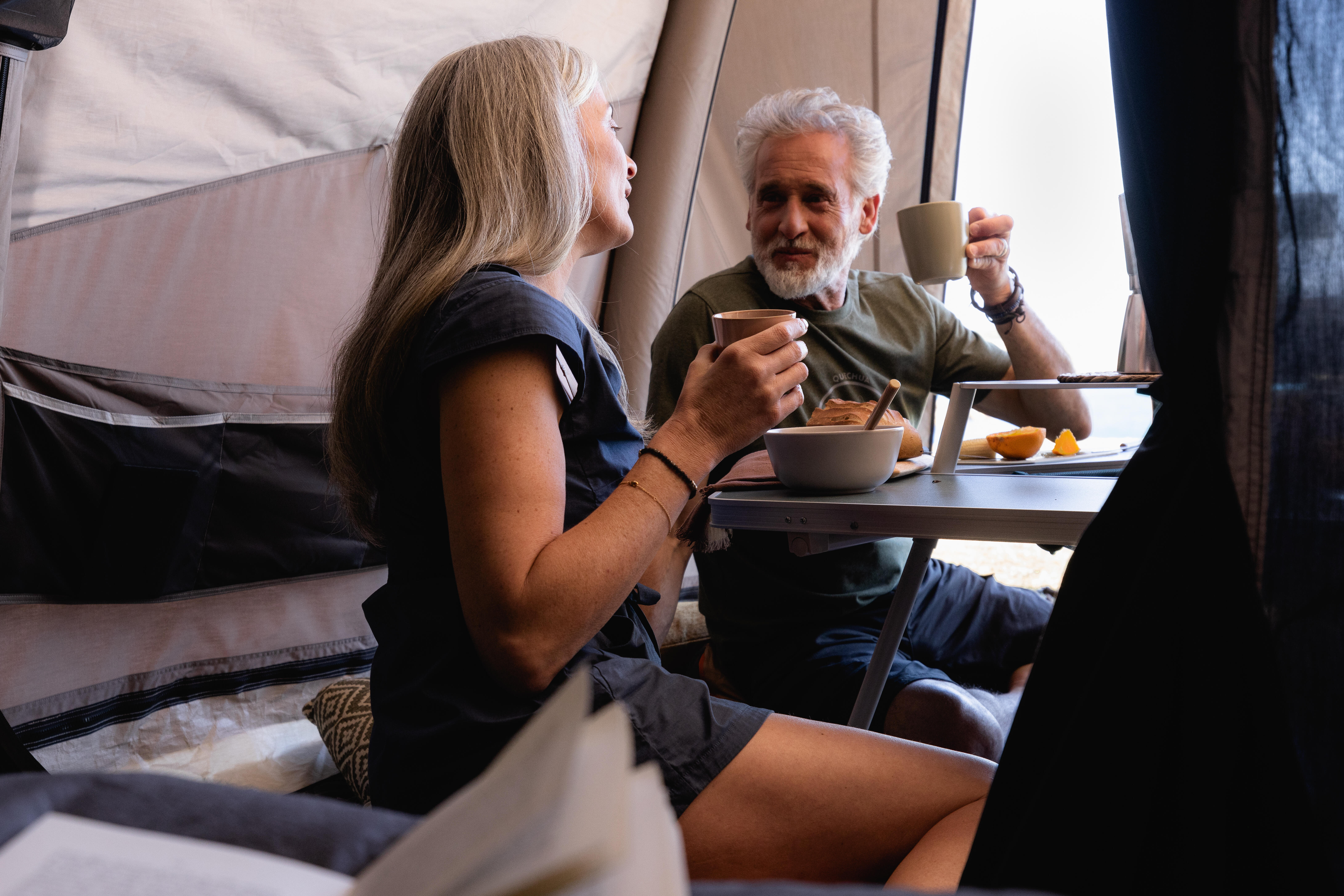 Couple enjoying breakfast at a camping table inside a family camping tent