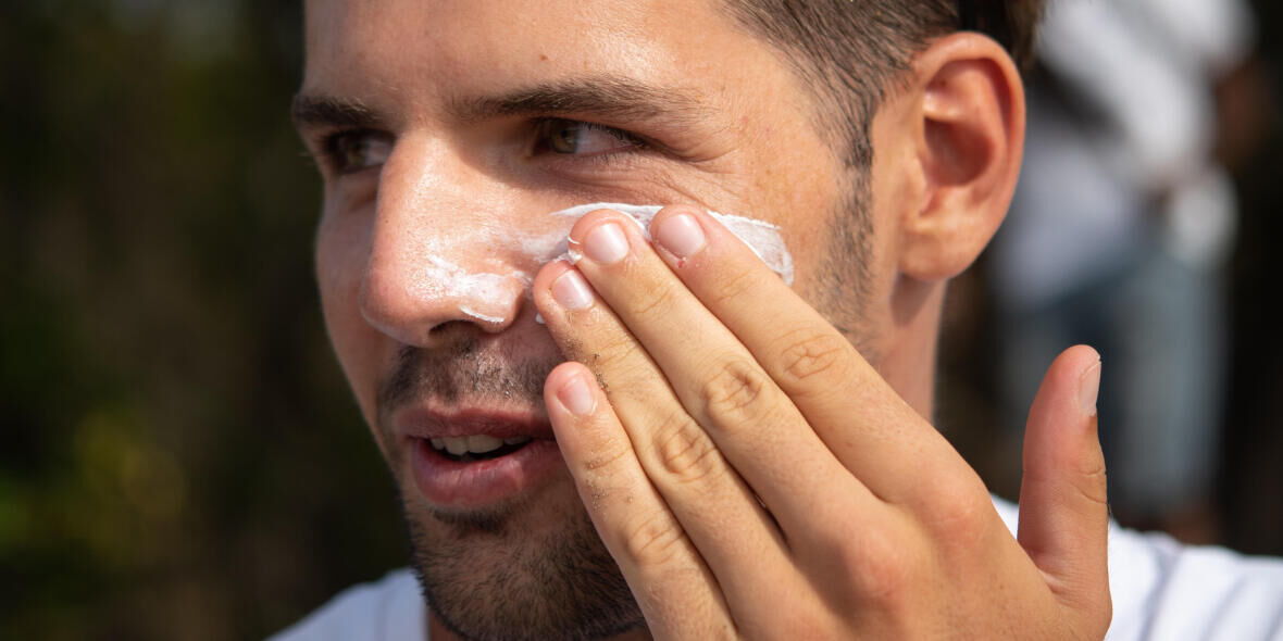 homem a aplicar protetor solar na face