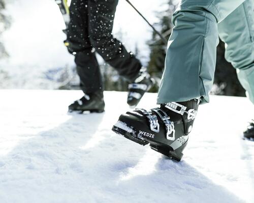 Narciarze idący po śniegu w butach narciarskich