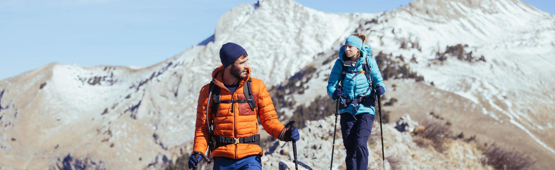 kobieta i mężczyzna wędrujący po górach z kijami trekkingowymi i plecakami turystycznymi na plecach