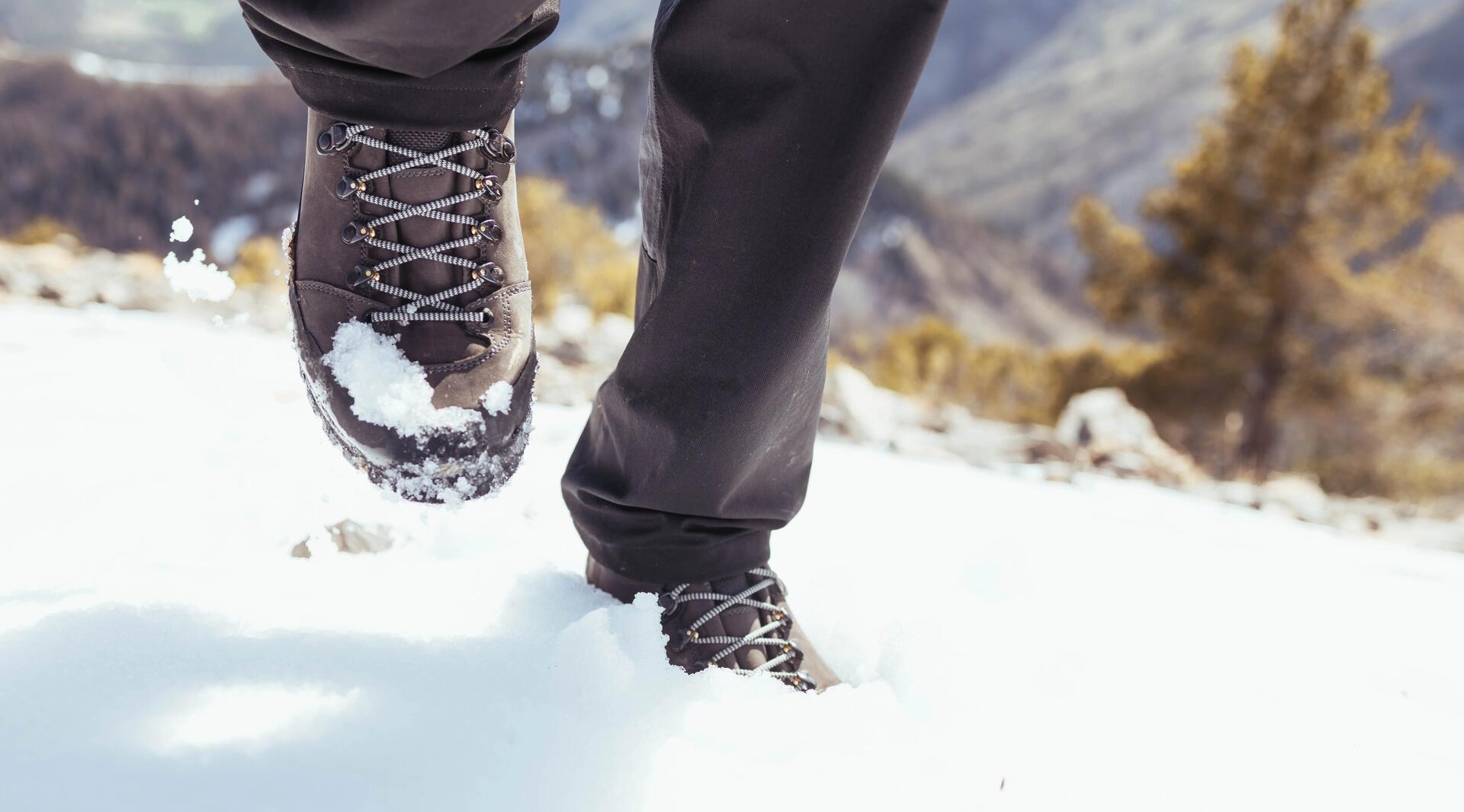 mężczyzna idący w butach trekkingowych po śniegu