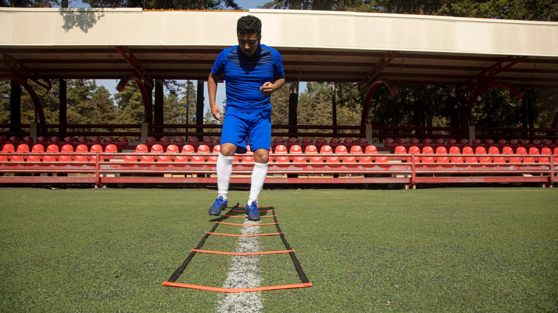 Voetballer die door een speedladder loop oefeningen doet.